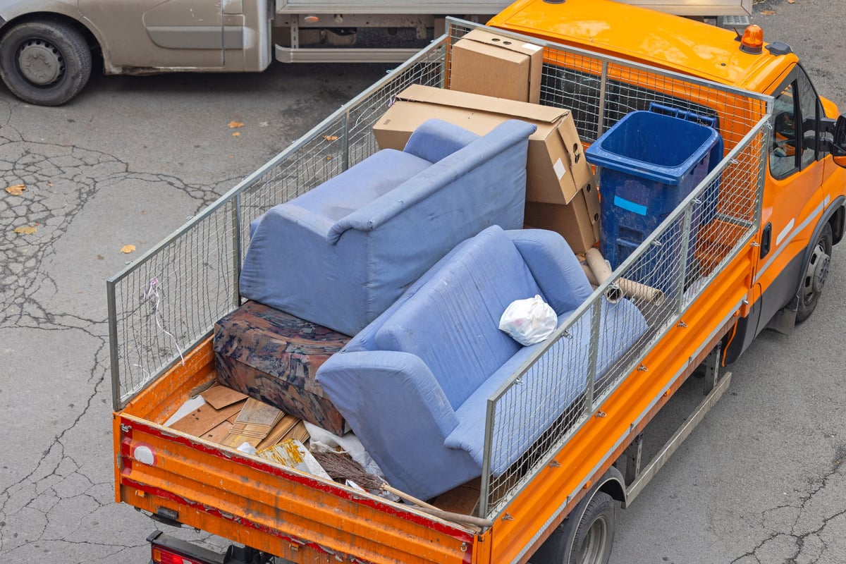 Aerial view of an old sofa and discarded furniture being removed into an open truck